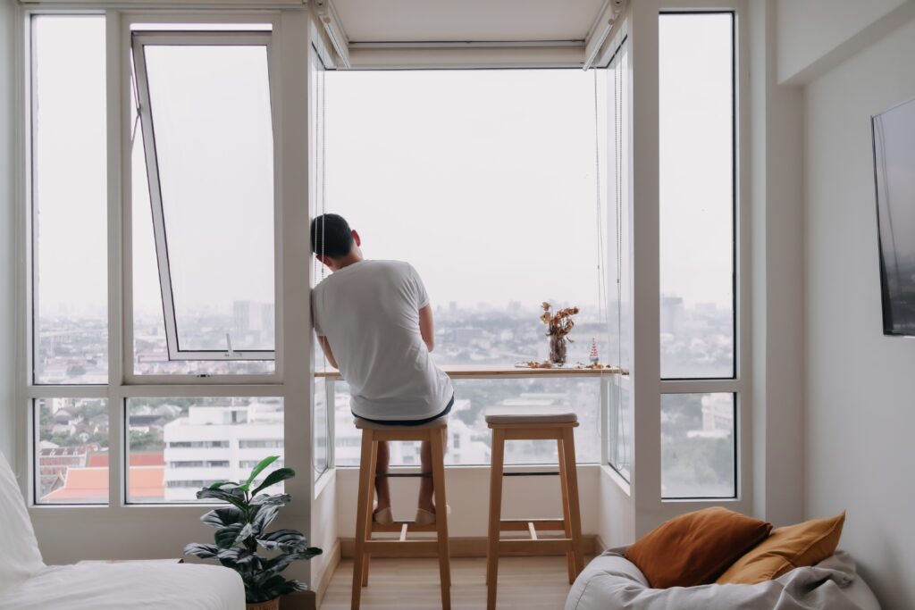 Man sitting on stool in front of window